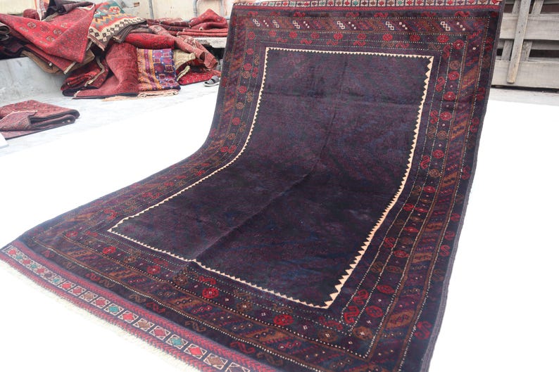 May include: A dark blue rug with a detailed floral pattern in shades of red, brown, and cream. The rug has a large central square with a smaller square inside, creating a frame effect.