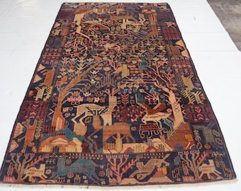 May include: A rectangular, hand-woven rug with a dark blue field and a detailed, colourful design. The rug features a central tree-of-life motif, with various animal figures and geometric patterns in shades of red, brown, and beige. The rug measures approximately 183 x 274 cm.