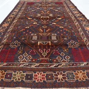 May include: A traditional Persian rug with a dark blue background and intricate floral patterns in shades of red, brown, and green. The rug has a fringed border and a central medallion.