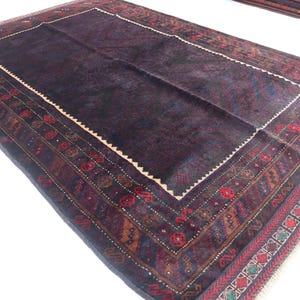May include: A dark blue rug with a detailed, multi-colored border. The border features geometric patterns and floral motifs in shades of red, orange, and green.