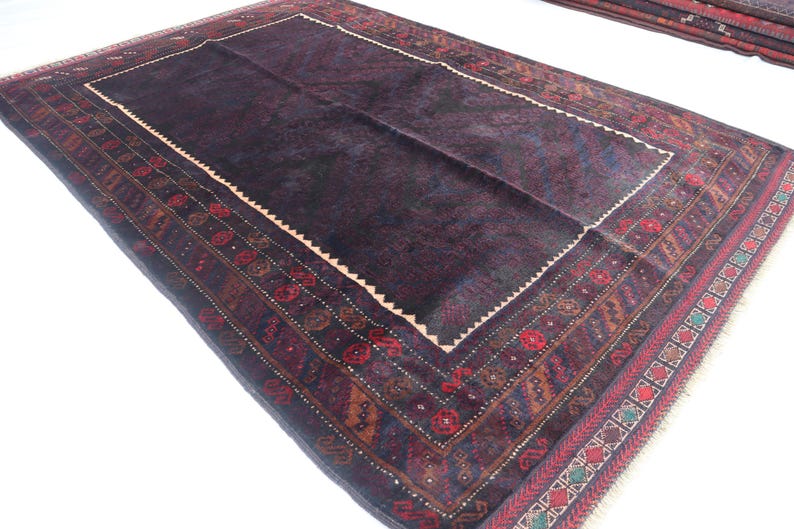 May include: A dark blue rug with a detailed, multi-colored border. The border features geometric patterns and floral motifs in shades of red, orange, and green.