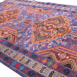 May include: A colorful rug with a geometric pattern in shades of blue, orange, red, and green. The rug has a border with a repeating pattern.