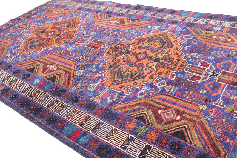 May include: A colorful rug with a geometric pattern in shades of blue, orange, red, and green. The rug has a border with a repeating pattern.