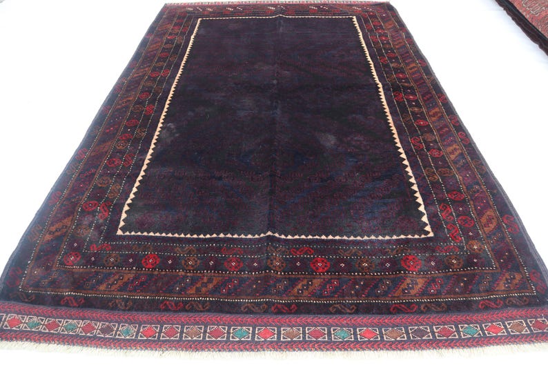 May include: A dark blue rug with a detailed, intricate pattern in shades of red, brown, and cream. The rug has a central field with a border of geometric designs.