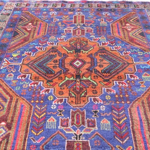May include: A colorful rug with a geometric pattern in shades of blue, orange, red, and green. The rug has a central medallion with a repeating pattern of triangles and diamonds.