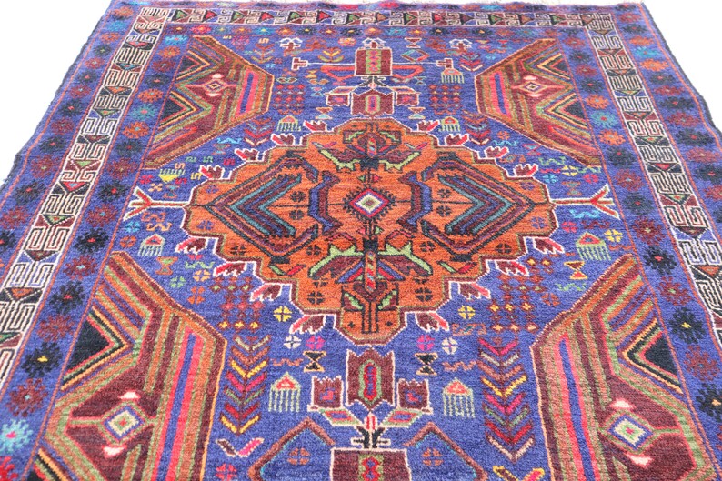 May include: A colorful rug with a geometric pattern in shades of blue, orange, red, and green. The rug has a central medallion with a repeating pattern of triangles and diamonds.