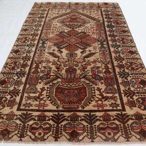 May include: A vintage rug with a beige background and intricate brown, red, and cream patterns. The rug features a central design with a floral motif and geometric shapes.