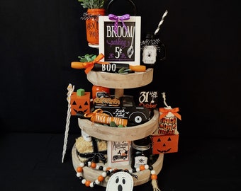 May include: A three-tiered wooden tray decorated with Halloween-themed items, including pumpkins, ghosts, and a sign that reads "Broom parking 5¢".