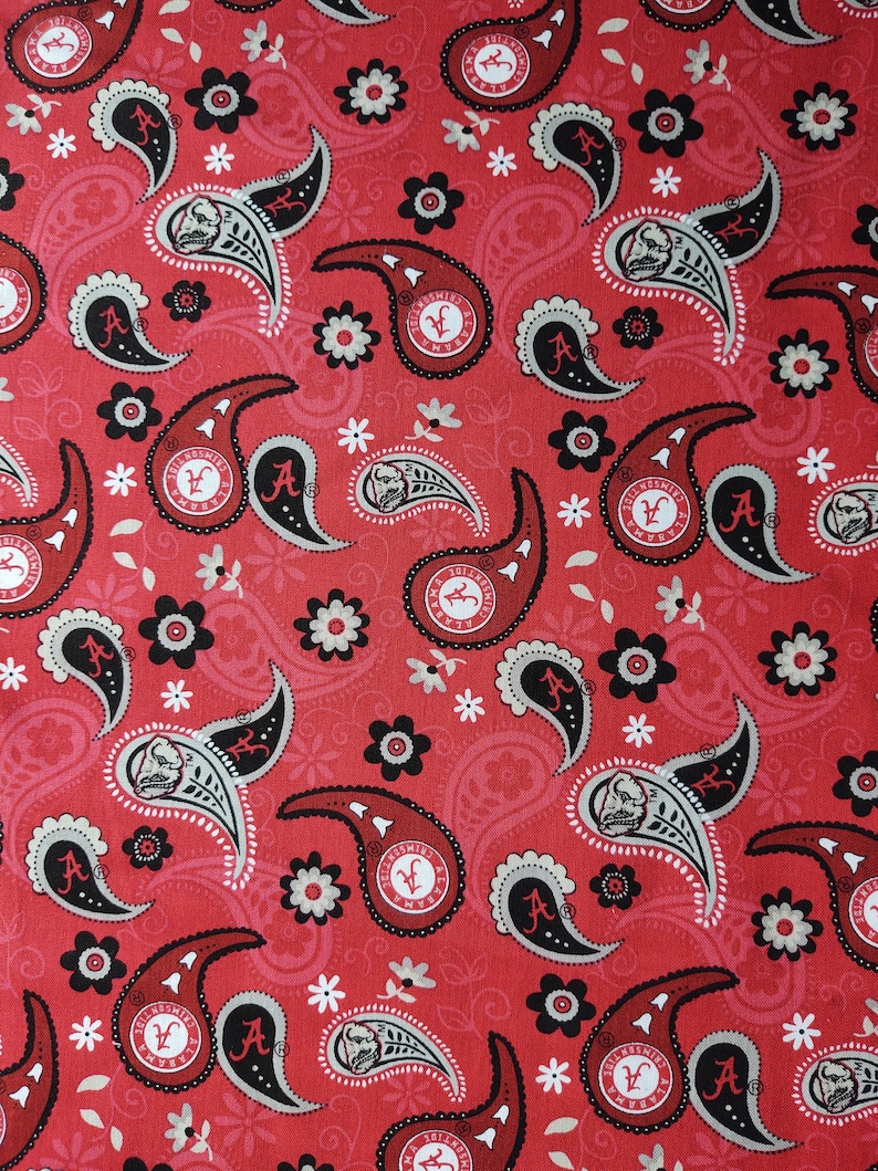 Puede incluir: Tela roja con un patr&oacute;n de paisley que presenta el logotipo de la Universidad de Alabama y un dise&ntilde;o de flores blancas.