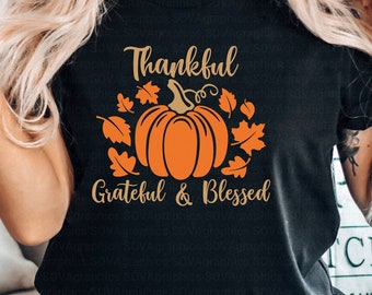 May include: A black t-shirt with a gold graphic of a pumpkin with leaves and the text "Thankful Grateful & Blessed".