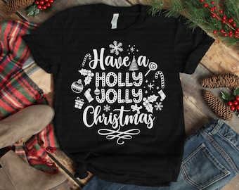 May include: Black t-shirt with the phrase "Have a Holly Jolly Christmas" in white script and festive graphics. The design includes snowflakes, candy canes, ornaments, and a Christmas tree.