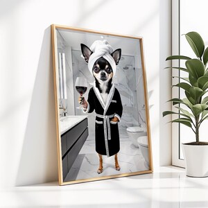May include: A framed print featuring a Chihuahua in a black robe and a white towel on its head, holding a glass of red wine. The dog is in a bathroom setting, with a white toilet and a marble-like shower visible in the background.