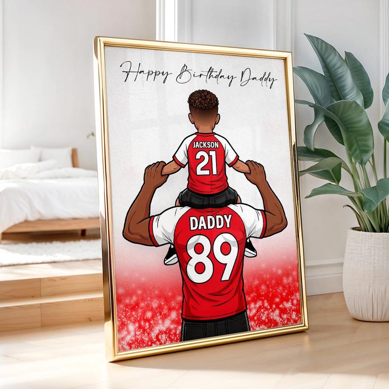Pu&ograve; includere: Stampa incorniciata con bordo dorato, raffigurante un'illustrazione a cartoni animati di padre e figlio. Il bambino &egrave; sulle spalle del padre, entrambi con maglie rosse e bianche con numeri. Il testo "Happy Birthday Daddy" &egrave; scritto in alto.