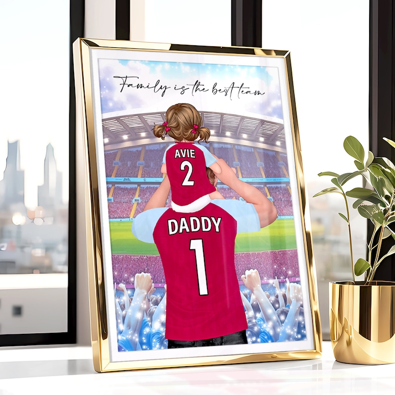 May include: A digital illustration of a father and daughter wearing matching soccer jerseys. The father is holding the daughter on his shoulders. The father's jersey says "Daddy 1" and the daughter's jersey says "Avie 2". The background is a blurred image of a soccer stadium with a crowd of people. The text "Family is the best team" is at the top of the image.
