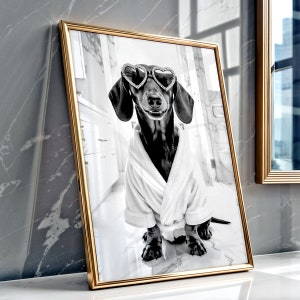 May include: A black and white photo of a dachshund wearing heart-shaped sunglasses and a white bathrobe. The dog is sitting on a white tiled floor.