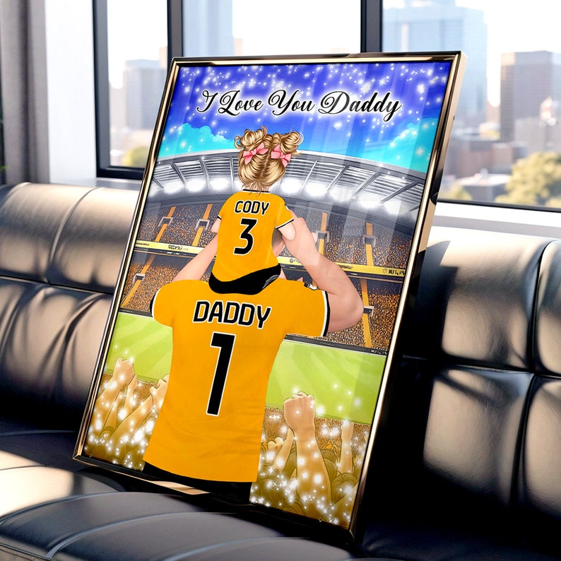 May include: A digital illustration of a father and child wearing matching soccer jerseys. The father's jersey says "Daddy 1" and the child's jersey says "Cody 3". The image is set against a backdrop of a stadium with a crowd of cheering fans. The text "I Love You Daddy" is written across the top of the image.