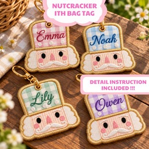Könnte beinhalten: Vier bestickte, nussknackerförmige Taschenanhänger mit goldenen Metallringen. Jeder Anhänger hat einen Hut mit Vichy-Karo-Muster und einen in Schreibschrift gestickten Namen: Emma in Pink, Noah in Blau, Lily in Grün und Owen in Lila. Die Gesichter haben rosa Wangen, schwarze Augen und weiße Schnurrbärte.