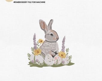 May include: Embroidered design of a gray bunny sitting in a nest of purple and yellow flowers and white speckled eggs.  The design includes the text "PES | JEF | EMB | EXP | DST".