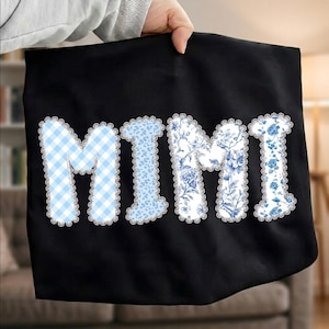 May include: Black tote bag with the word "MIMI" in large letters. The letters are decorated with blue and white patterns, including gingham and floral designs, and are outlined with white lace trim.
