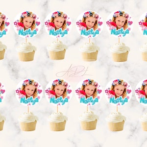 May include: Twelve cupcake toppers with a round, white background featuring a girl's photo, pink and blue flowers, and the text "I love Nastya".