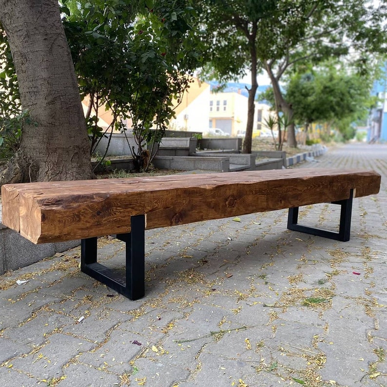 May include: A rustic wooden bench with a natural brown finish and black metal legs. The bench is made from reclaimed wood and has a unique, handcrafted look.