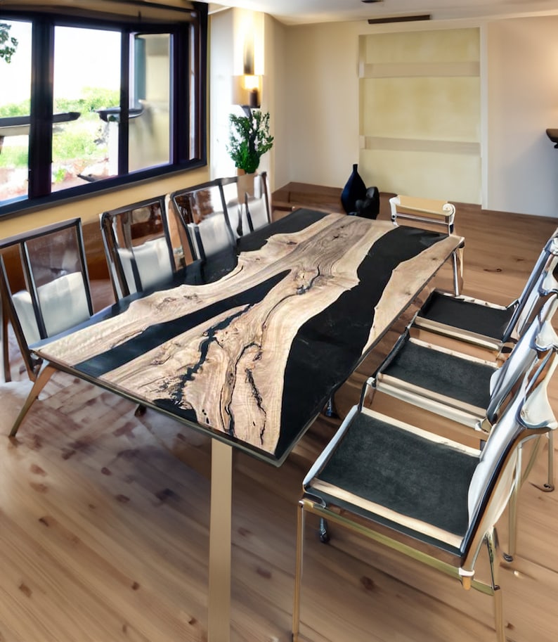 May include: A large wooden dining table with a black epoxy resin inlay. The table has a natural wood grain pattern and is supported by four metal legs. The table is surrounded by six chairs with black fabric seats and chrome frames.