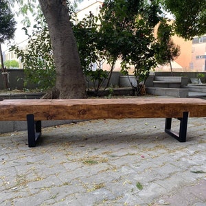 May include: A rustic wooden bench with a natural brown finish and black metal legs. The bench is made from reclaimed wood and has a unique, handcrafted look.