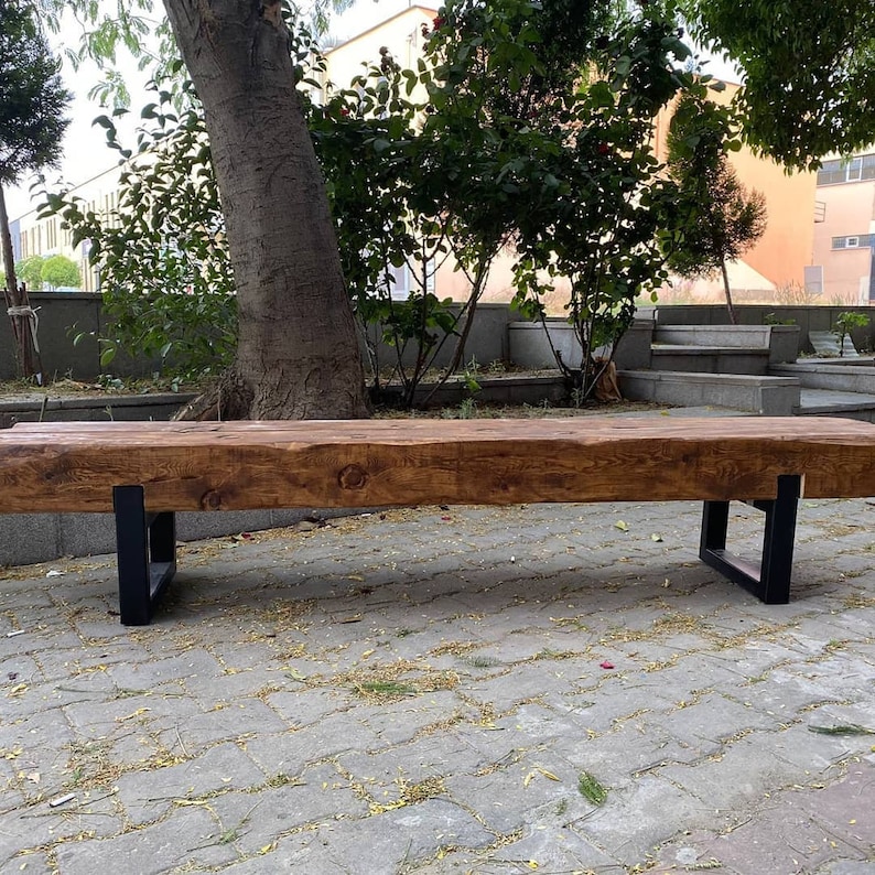 May include: A rustic wooden bench with a natural brown finish and black metal legs. The bench is made from reclaimed wood and has a unique, handcrafted look.