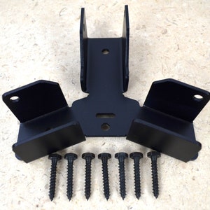 May include: Black metal bracket set with mounting hardware. The set includes a central bracket with two uprights, two side brackets, and seven black screws. The components are arranged on a light-colored surface.