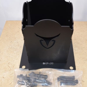 May include: A black, laser-cut organiser with a decorative bull head design. The organiser has a square base and a curved top. Two clear plastic bags containing screws and bolts are in front of the organiser.