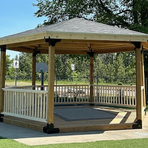 May include: A wooden hexagonal gazebo with a shingled roof and a white railing. The gazebo has a wooden floor and a gray rug inside.
