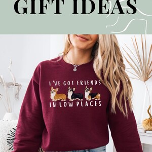 May include: A maroon sweatshirt with a graphic of three corgis and the text "I've got friends in low places".