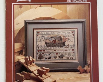 May include: A vintage issue of Leisure Arts magazine, featuring a cross stitch pattern of a boat with the text "Shorty days, Shorty nights, Shorty days". The magazine cover also features a wooden toy set with a ramp and animals.