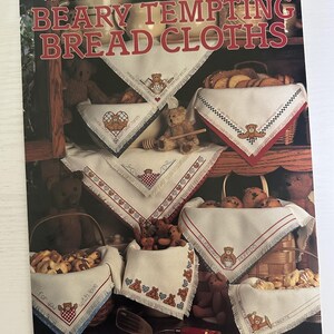 May include: A leaflet titled "BEARY TEMPTING BREAD CLOTHS" by Jane Chandler. The cover features various white bread cloths with embroidered teddy bear designs and red and blue borders. Baskets of bread and teddy bears are also visible.