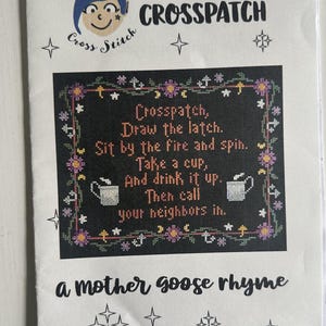May include: A cross-stitch pattern featuring the text "Crosspatch, Draw the latch. Sit by the fire and spin. Take a cup, And drink it up. Then call your neighbors in." The design includes floral and star motifs, and the words "a mother goose rhyme."