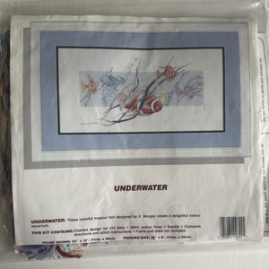 May include: Cross-stitch kit featuring an underwater scene with colorful tropical fish. The design includes fish, coral, and bubbles, framed in a light blue border. The kit includes floss and instructions. Finished size is 16" x 8".