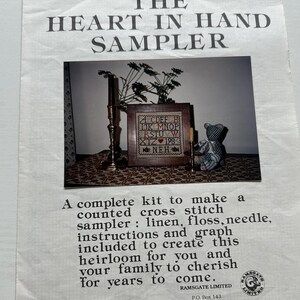 May include: A cross stitch sampler kit with a picture of a completed sampler featuring the alphabet, a heart, and the year 198. The kit includes linen fabric, floss, a needle, instructions, and a graph. The kit is for creating a heirloom to cherish for years to come.