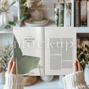 May include: A person is holding open a magazine with a green chair on the front cover. The magazine title is "Designing Today".