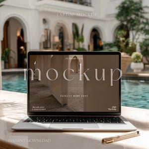 May include: A silver laptop computer with a black screen displaying a mockup design with the text "Introducing mockup" and "Elegant Serie Font". The laptop is sitting on a white surface with a gold pen and the text "Instant Download" and "PSD File" visible.