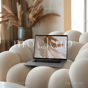 May include: A laptop computer with a white background on the screen that says "soul of the essay" and "est. 1951" is sitting on a white, cloud-shaped sofa.