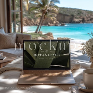 May include: A gold laptop computer with a white keyboard and a screen displaying a mockup of a logo for a company called "Botanicals". The laptop is sitting on a white couch with a white blanket and a cup of coffee on a saucer. The background is a blurry image of a beach with palm trees and blue water.