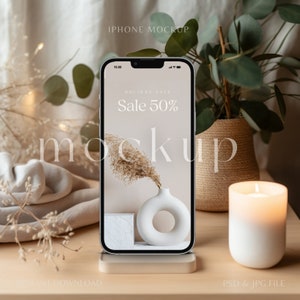 May include: A white iPhone mockup with a beige background and a vase with a dried flower. The phone screen displays a sale advertisement with the text "Holiday Sale Sale 50%".