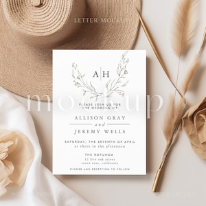 May include: A white wedding invitation with a floral wreath and the initials "AH" in the center. The text reads "Please join us for the wedding of Allison Gray and Jeremy Wells, Saturday, the seventh of April at three in the afternoon, The Rotunda, 12 live oak street, santa rosa, california, Dinner and reception to follow."