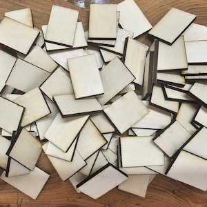 May include: A large pile of unfinished wooden rectangular tags with black edges. The tags are all the same size and shape, and they are arranged in a random order.