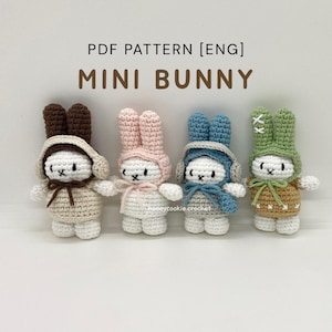 May include: Four crocheted mini bunny figures in beige, pink, blue, and green. Each bunny wears a different hat and scarf. The text "PDF PATTERN [ENG] MINI BUNNY" is displayed above the bunnies.