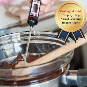 May include: A digital thermometer with a silver probe is inserted into a pot of melted chocolate. The thermometer reads 103 degrees. A wooden spoon is in the pot of chocolate.
