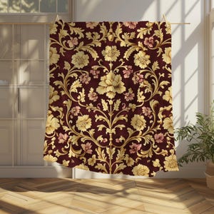 Pode incluir: Um tecido bordô com um padrão de damasco floral dourado e rosa. O tecido apresenta detalhes intrincados e um design repetitivo.