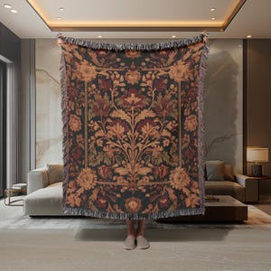 May include: A tapestry throw blanket with a dark background and intricate floral patterns in shades of red, orange, and gold. The blanket has a fringe border.