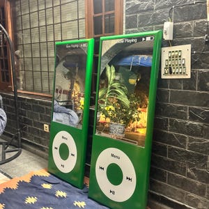 May include: Two large, rectangular, green mirrors designed to resemble classic portable music players. Each mirror features a white circular control interface with a central button, playback icons, and the text Menu. The top section displays Now Playing.