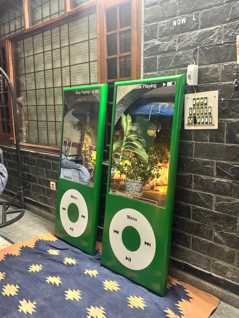 May include: Two large, rectangular, green mirrors designed to resemble classic portable music players. Each mirror features a white circular control interface with a central button, playback icons, and the text Menu. The top section displays Now Playing.